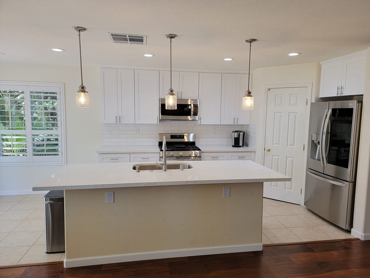 Open-concept kitchen remodel with a white island and pendant lights by H&H Builds in Sacramento, CA