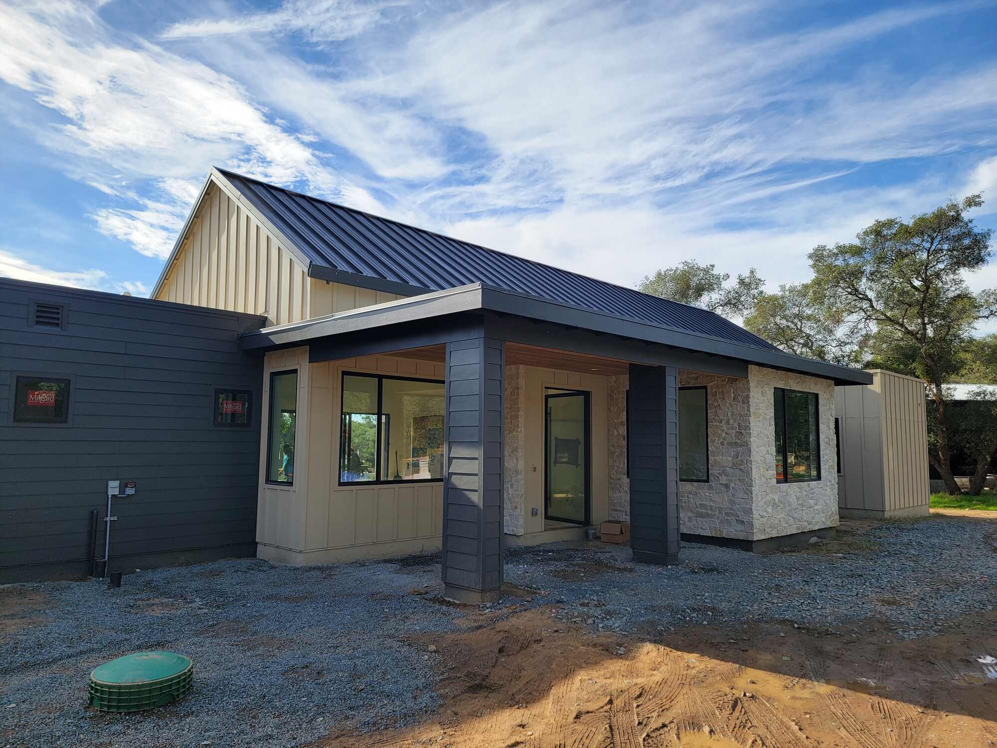 Modern custom home exterior featuring stone finishes, black siding, and a gabled roof by H&H Builds in Sacramento, CA