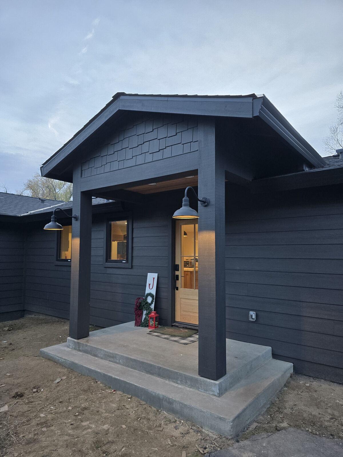 Exterior view of a remodeled home with dark siding and modern porch lighting by H&H Builds in Sacramento, CA