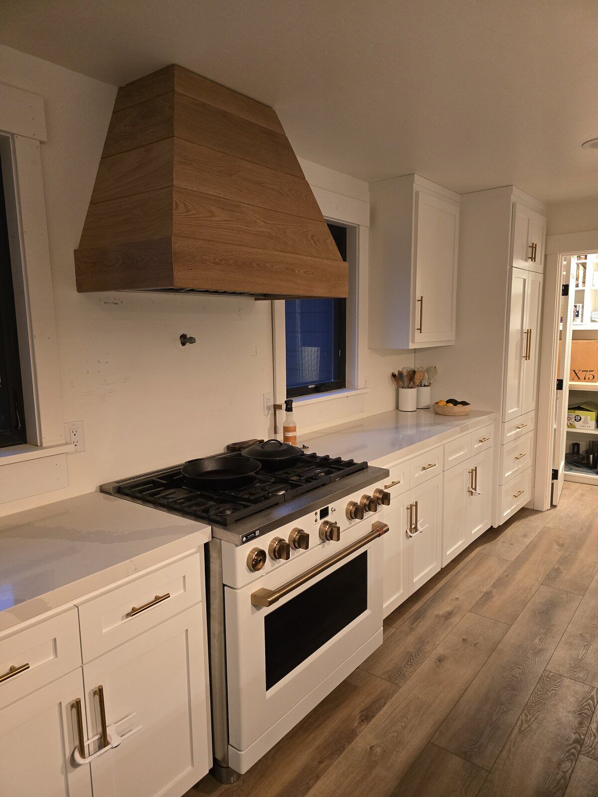 Kitchen remodel featuring white cabinetry, gold hardware, and a wooden range hood in Sacramento, CA, by H&H Builds