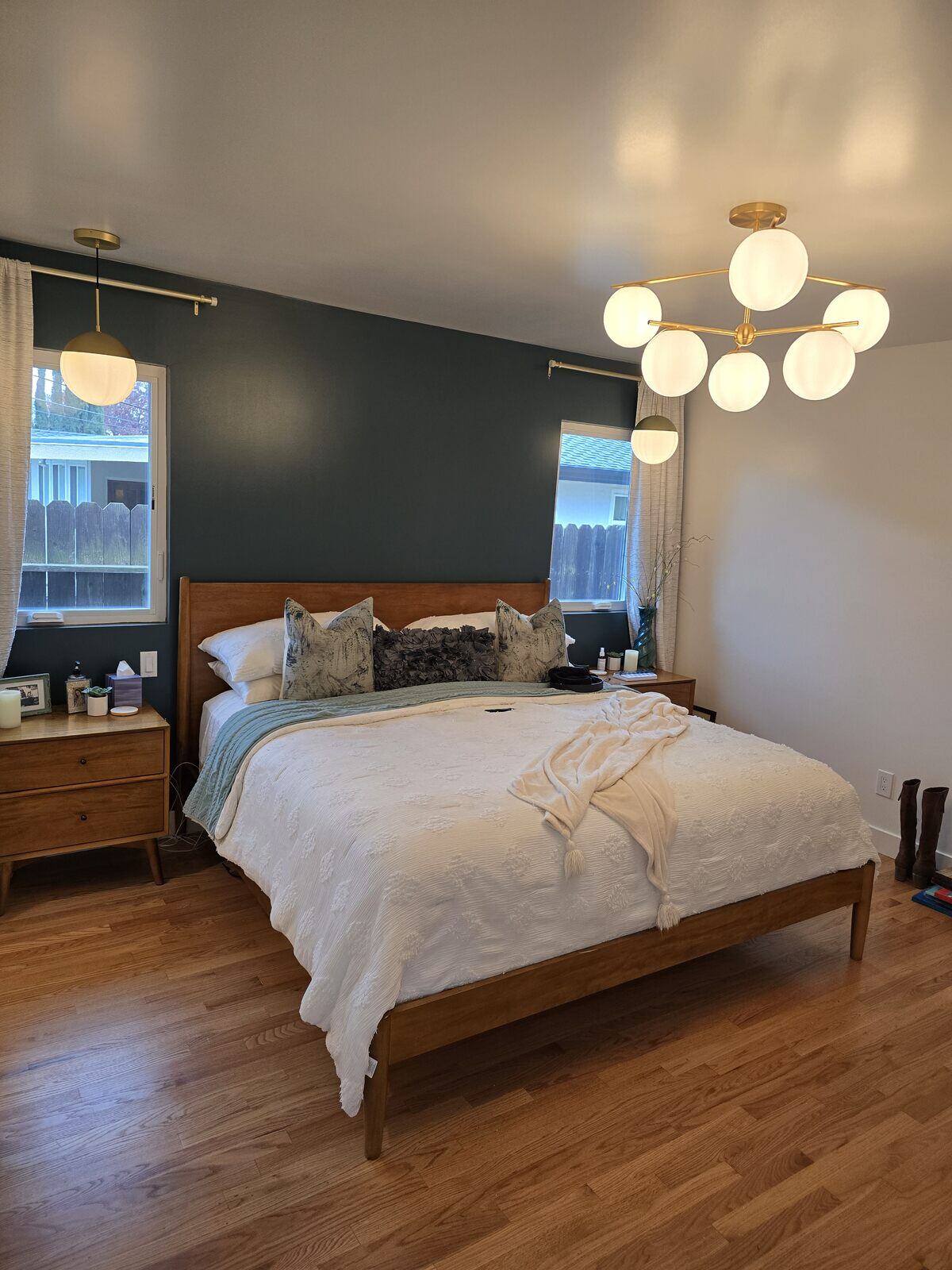 Modern master bedroom remodel with wood floors, green accent wall, and stylish lighting fixtures by H&H Builds, Sacramento, CA