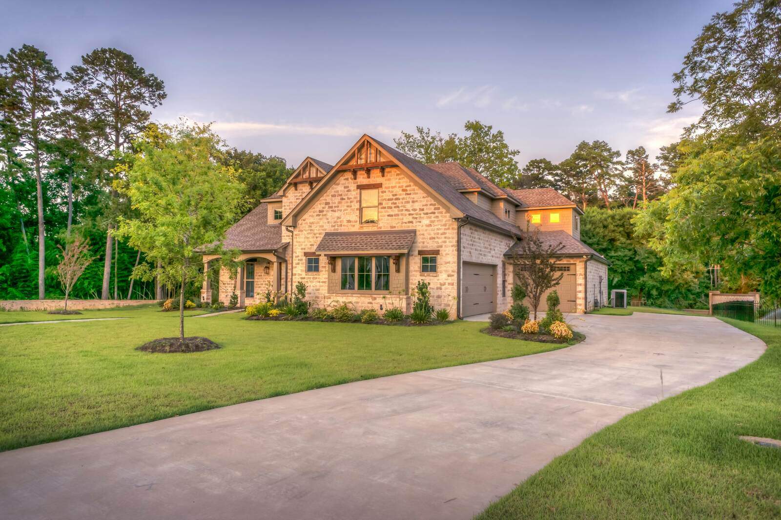 Beautiful stone custom-built home with lush green landscaping by H&H Builds in Sacramento, CA