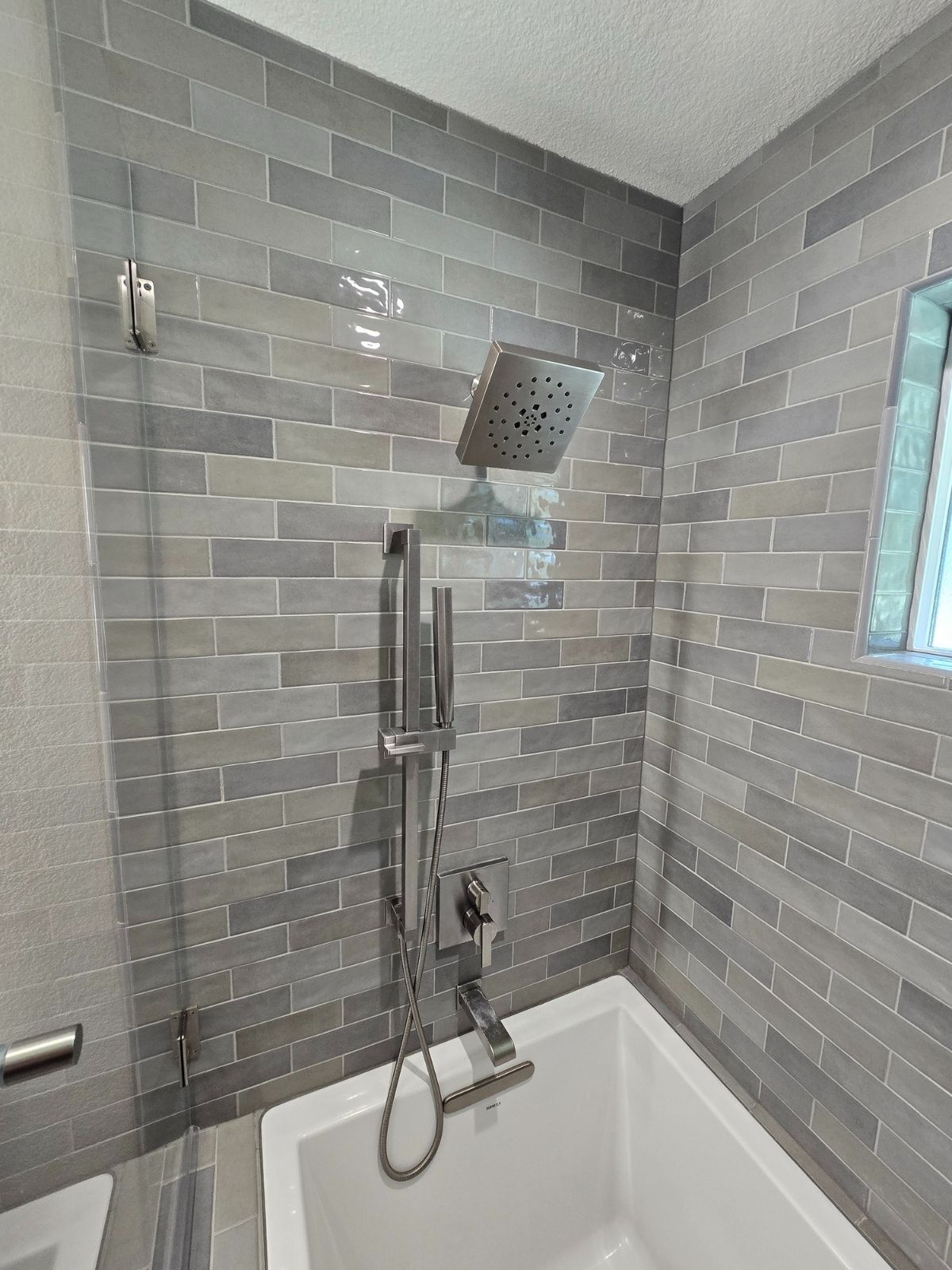 Modern bathroom shower with gray subway tile and square rainfall showerhead located in Sacramento