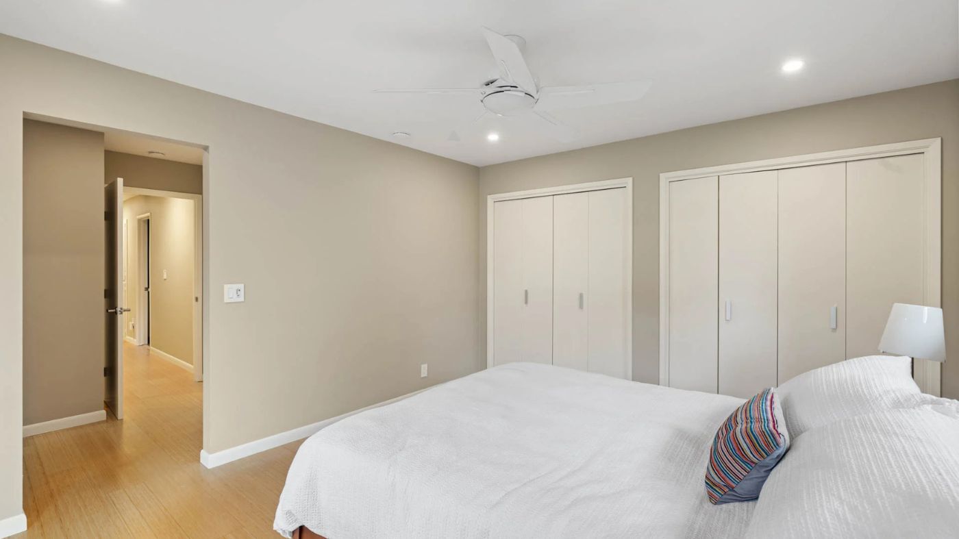 Sacramento bedroom with neutral walls, bamboo floors, dual closets, and a ceiling fan above a neatly made bed