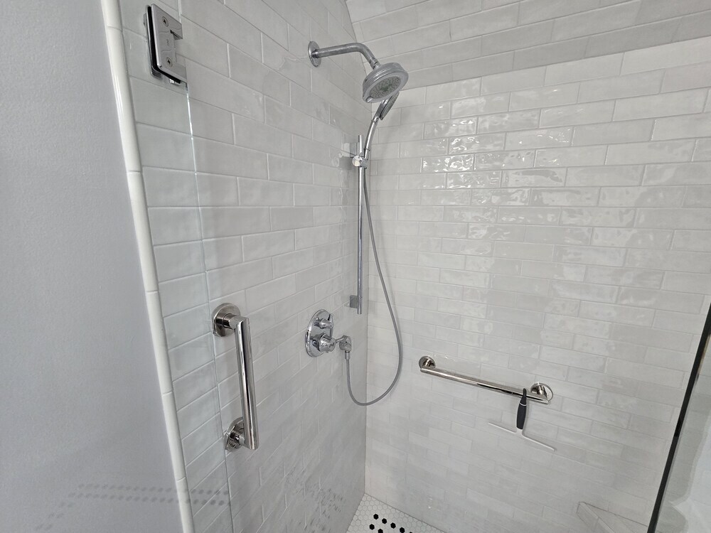 Shower with handheld options, grab bar, white glossy subway tile and nickel fixtures